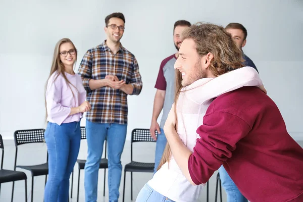 Young man calming his friend at group therapy session — Stock Photo, Image