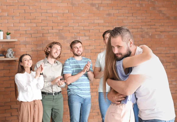 Young man calming his friend at group therapy session — Stock Photo, Image