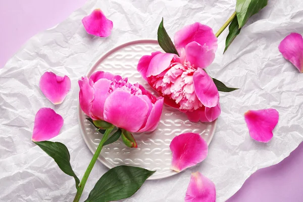 Vackra pion blommor och tallrik på skrynkliga papper — Stockfoto