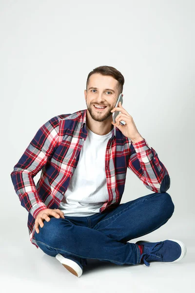 Bonito homem falando por telefone no fundo branco — Fotografia de Stock