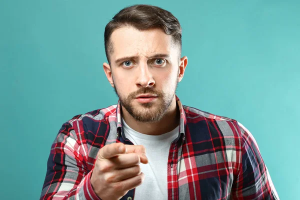 Portrait of frowning man pointing at viewer on color background — Stock Photo, Image
