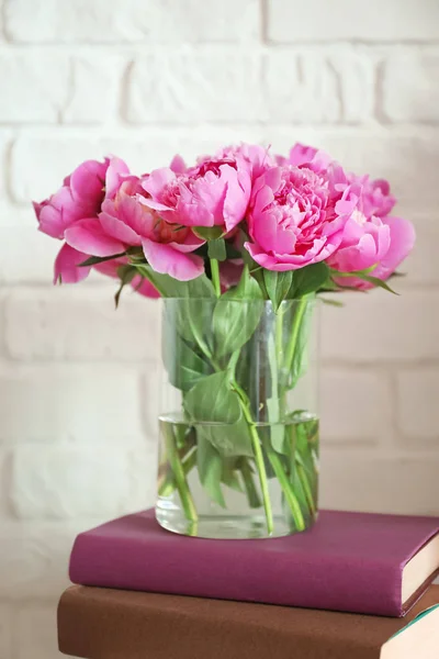 Vase with beautiful peony flowers and books on white background — Stock Photo, Image