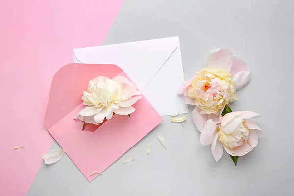 Mooie Peony bloemen en enveloppen op lichte achtergrond — Stockfoto