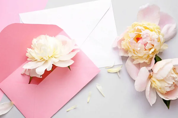 Hermosas flores de peonía y sobres sobre fondo claro — Foto de Stock