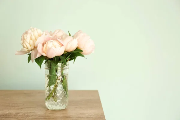 Jarrón con hermosas flores de peonía en la mesa contra el fondo de color — Foto de Stock