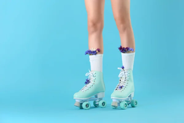 Ноги женщины в винтажных роликовых коньках и с цветами на фоне цвета — стоковое фото