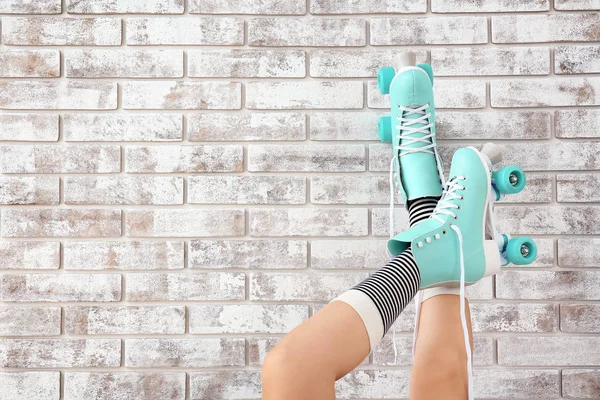 Pernas de mulher em patins contra parede de tijolo — Fotografia de Stock