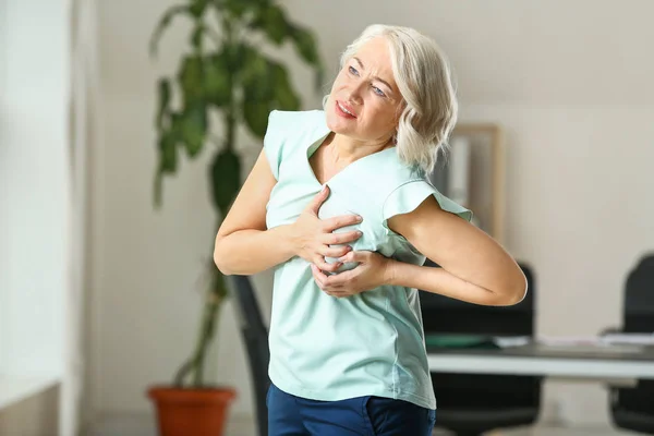 Mature woman suffering from heart attack in office — Stock Photo, Image