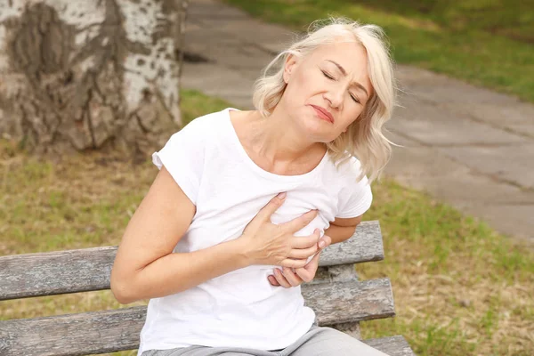 Mature woman suffering from heart attack outdoors — Stock Photo, Image