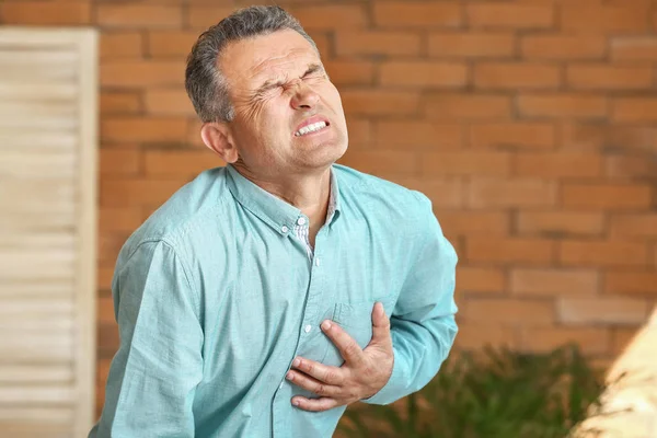 Mature man suffering from heart attack at home — Stock Photo, Image