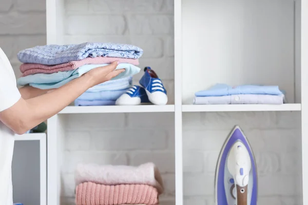 Frau stellt Stapel sauberer Kleidung zu Hause ins Regal — Stockfoto