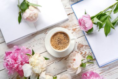 Şakayık lı bir fincan kahve ve beyaz masada kitaplar