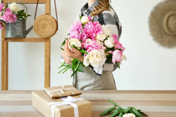 Female florist with beautiful bouquet of peonies in shop