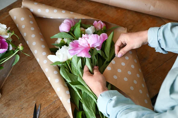 Vrouw maken boeket van mooie Pioenen aan tafel — Stockfoto