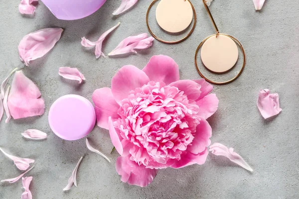 Beautiful peony with earrings and cosmetics on grey background — Stock Photo, Image