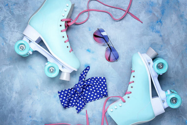Vintage roller skates and accessories on color background