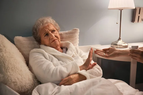Senior woman refusing to take medicine against insomnia at night — Stock Photo, Image