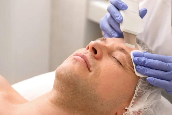 Handsome man undergoing procedure of facial peeling in beauty salon — Stock Photo, Image