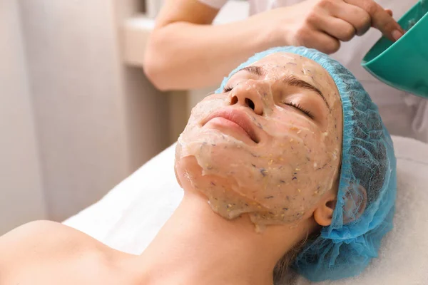 Vacker kvinna som genomgår behandling med ansiktsmask i skönhetssalongen — Stockfoto