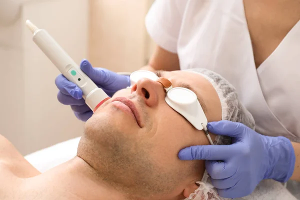Handsome man undergoing procedure of laser biorevitalization in beauty salon — Stock Photo, Image