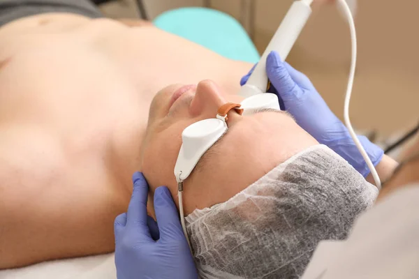 Handsome man undergoing procedure of laser biorevitalization in beauty salon — Stock Photo, Image