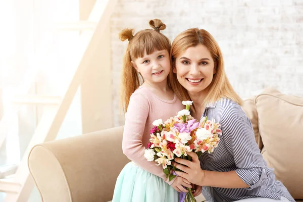 Little girl greeting her mother with bouquet of flowers at home — Stock Photo, Image