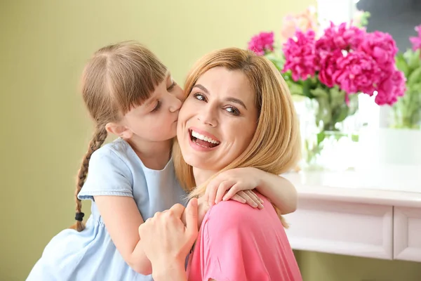 Маленькая девочка целует мать дома — стоковое фото