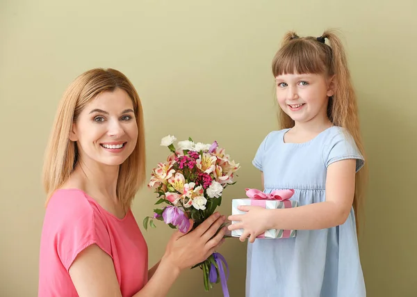 Little girl greeting her mother on color background — Stock Photo, Image