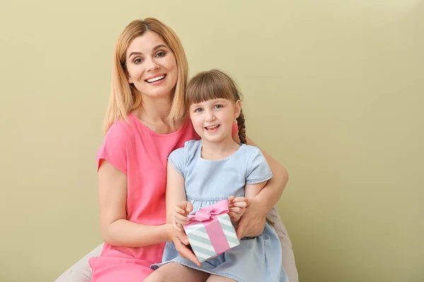 Little girl greeting her mother on color background — Stock Photo, Image