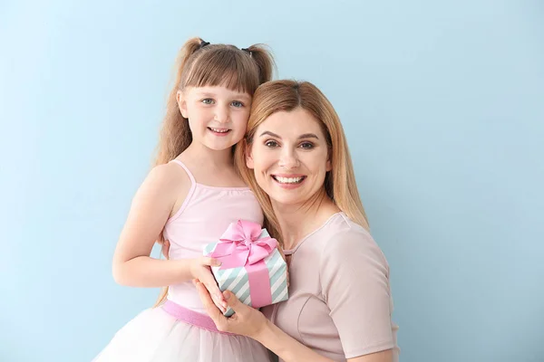 Little girl greeting her mother on color background — Stock Photo, Image