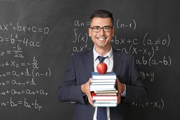 Beau professeur de mathématiques avec des livres près du tableau noir en classe — Photo