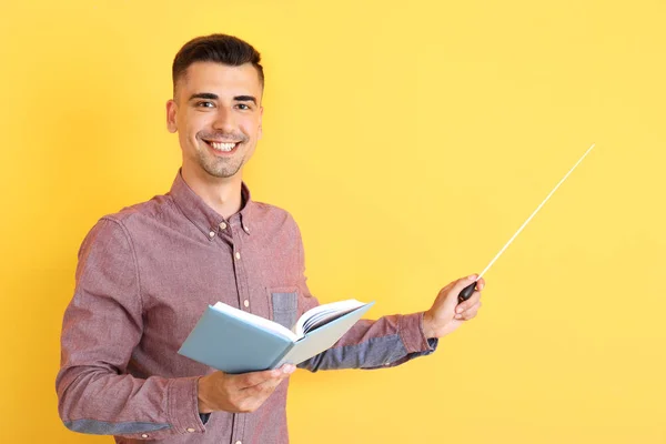 Guru tampan laki-laki dengan buku dan pointer di latar belakang warna — Stok Foto