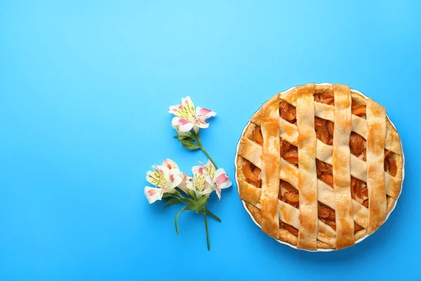 Torta de pêssego saboroso e flores no fundo de cor — Fotografia de Stock