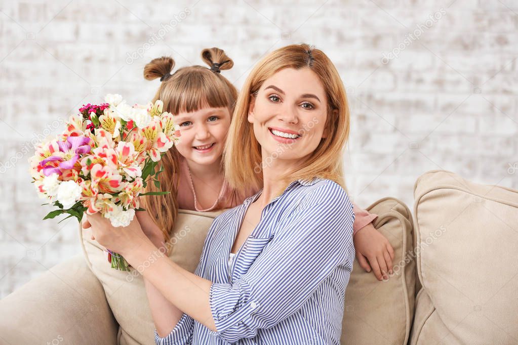 Little girl greeting her mother with bouquet of flowers at home