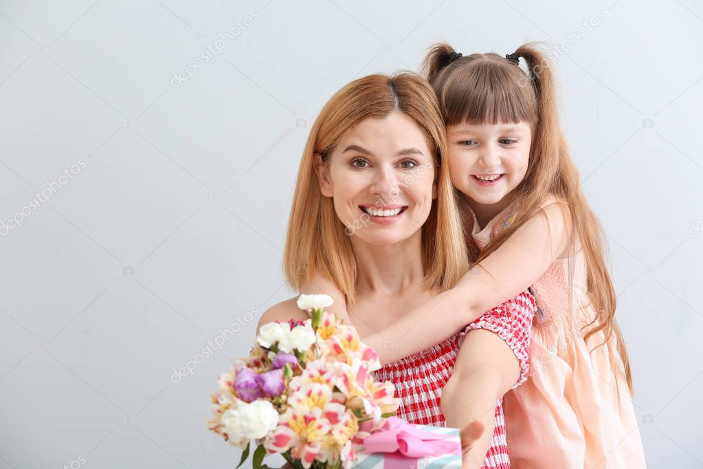 Little girl greeting her mother on light background
