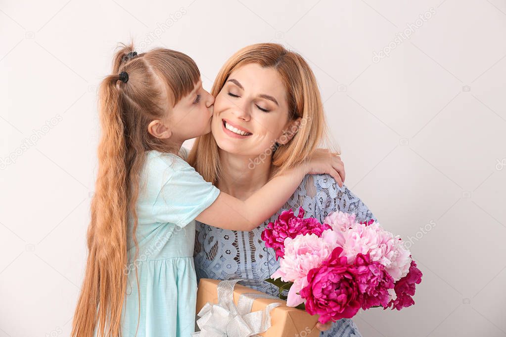 Little girl greeting her mother on color background