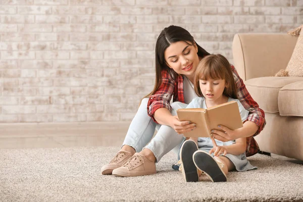 Portrait of happy mother and daughter reading book at home — Stock Photo, Image