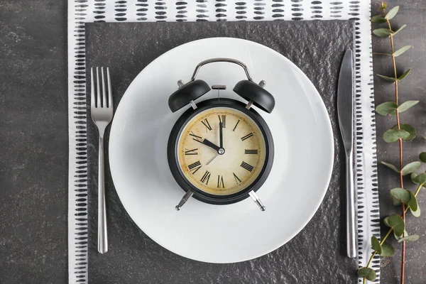 Simple table setting with alarm clock on dark background