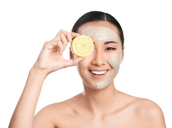 Beautiful Asian woman with facial mask and lemon on white background — Stock Photo, Image