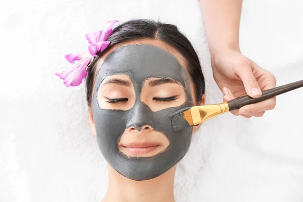 Vacker asiatisk kvinna som genomgår behandling med ansikts mask i skönhets salong — Stockfoto