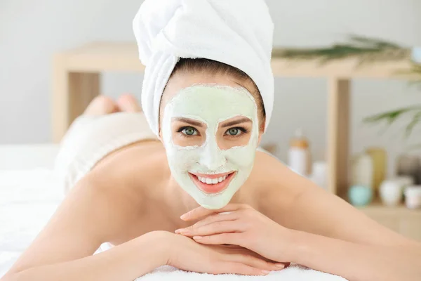 Hermosa mujer joven en tratamiento con mascarilla facial en salón de belleza —  Fotos de Stock