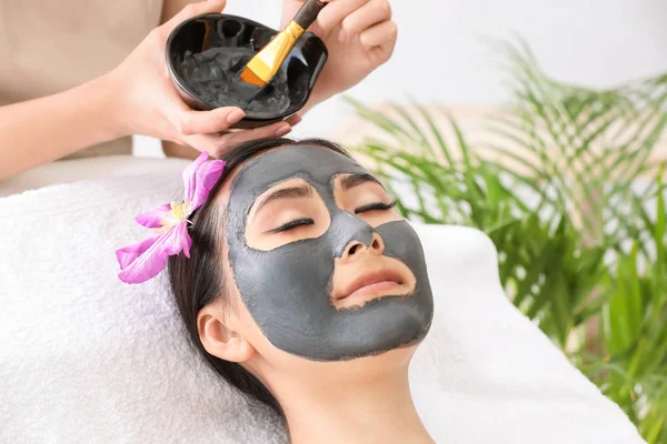 Vacker asiatisk kvinna som genomgår behandling med ansikts mask i skönhets salong — Stockfoto