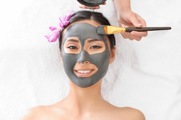 Beautiful Asian woman undergoing treatment with facial mask in beauty salon — Stock Photo, Image