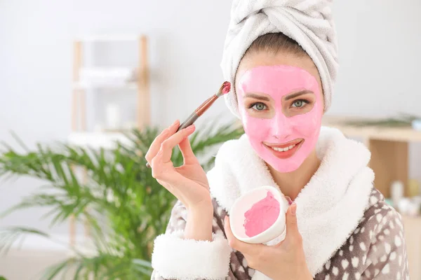 Beautiful young woman applying facial mask at home — Stock Photo, Image