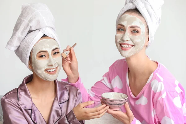 Hermosas mujeres jóvenes aplicando máscaras faciales en casa — Foto de Stock