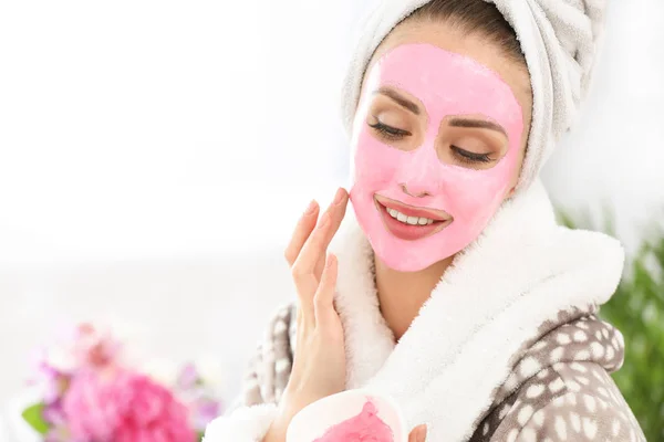Mooie jonge vrouw met gezichtsmasker thuis — Stockfoto