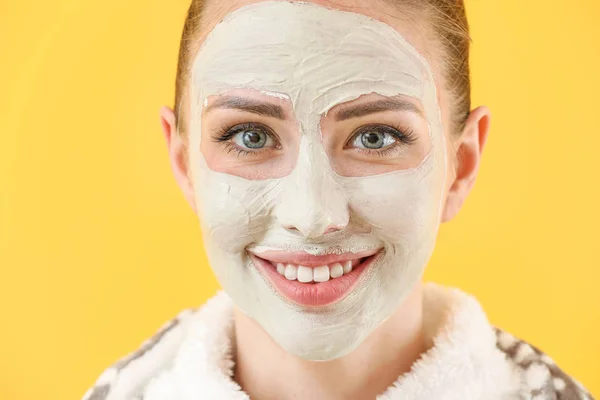 Beautiful young woman with facial mask on color background — Stock Photo, Image