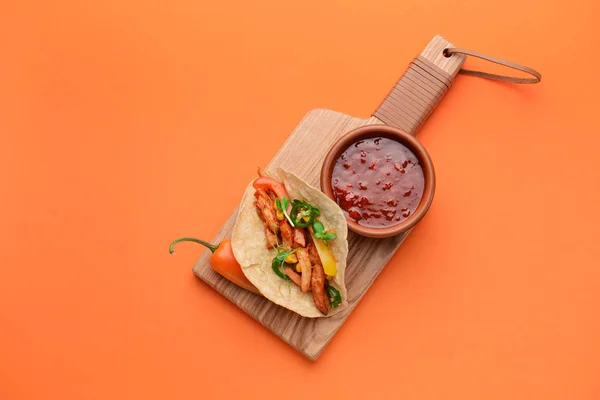 Board with tasty fresh taco and sauce on color background — Stock Photo, Image