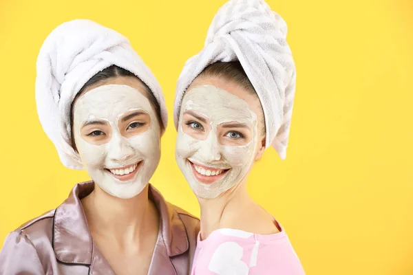 Красиві молоді жінки з масками для обличчя на кольоровому фоні — стокове фото