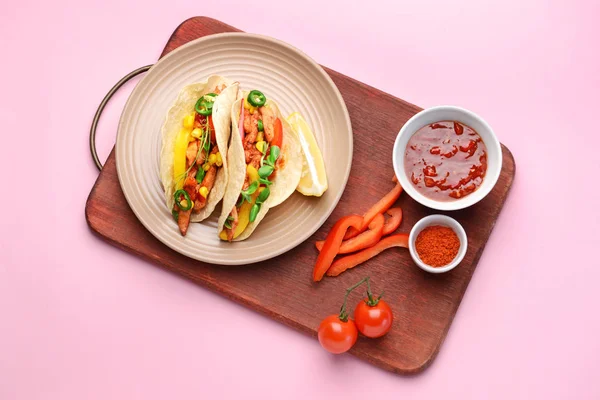 Piatto con gustosi tacos freschi e salsa su sfondo colore — Foto Stock